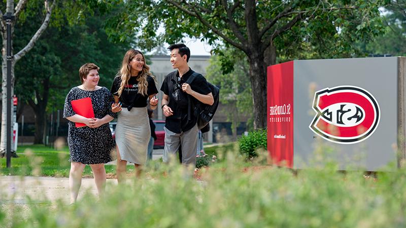 Three students walking outside Admissions