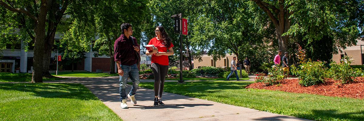 Two students walking with books in hands